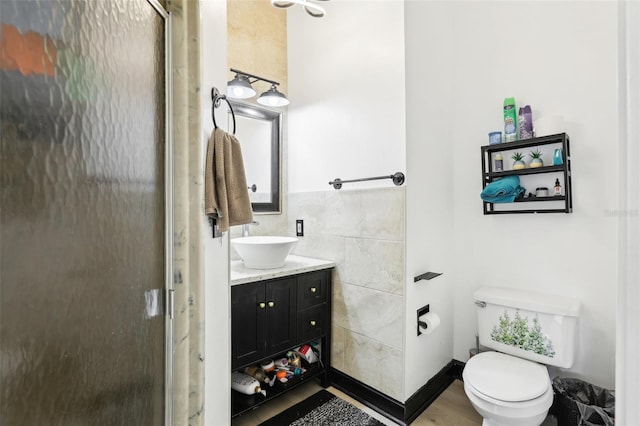 bathroom featuring a shower stall, tile walls, vanity, and toilet