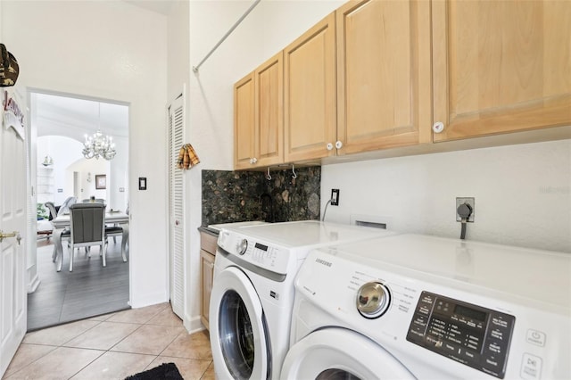 clothes washing area featuring washer and clothes dryer, a notable chandelier, cabinet space, and light tile patterned flooring