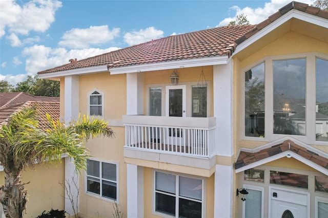 view of home's exterior featuring stucco siding, a balcony, and a tiled roof