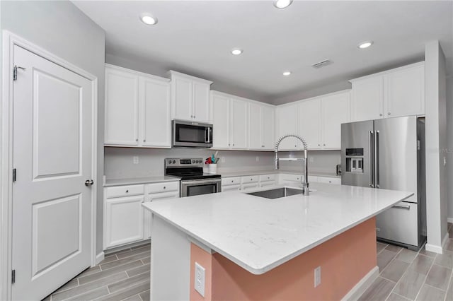 kitchen featuring a sink, white cabinets, a center island with sink, and stainless steel appliances