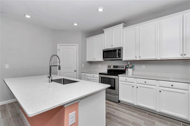 kitchen featuring an island with sink, a sink, recessed lighting, stainless steel appliances, and white cabinets