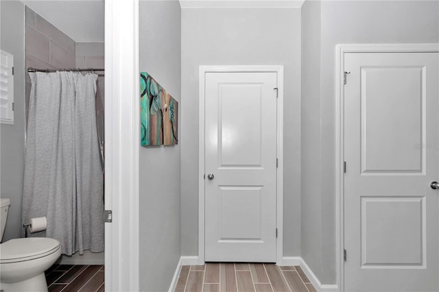 bathroom featuring curtained shower, toilet, baseboards, and wood tiled floor