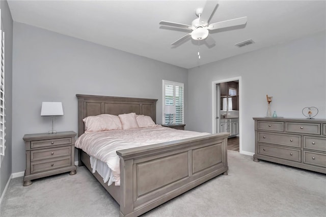 bedroom with visible vents, ensuite bath, baseboards, light colored carpet, and ceiling fan