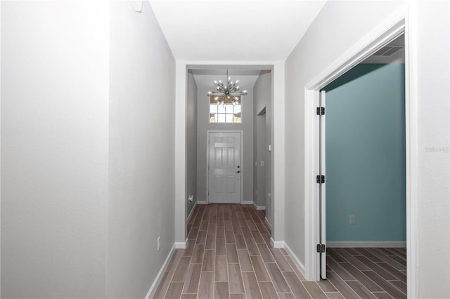 corridor with visible vents, an inviting chandelier, baseboards, and wood tiled floor