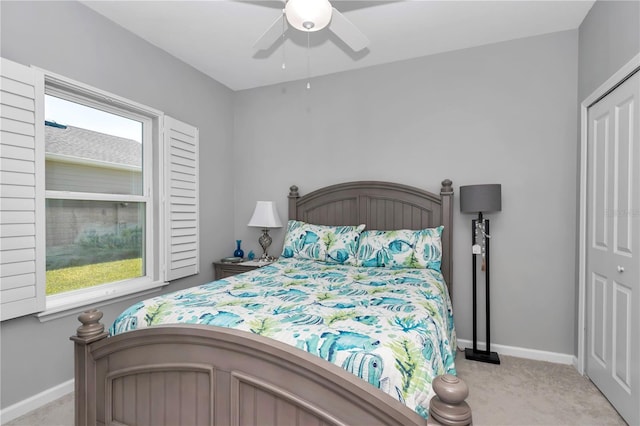 bedroom featuring light carpet, ceiling fan, a closet, and baseboards