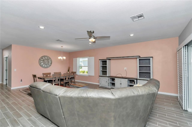 living area featuring visible vents, ceiling fan with notable chandelier, and baseboards