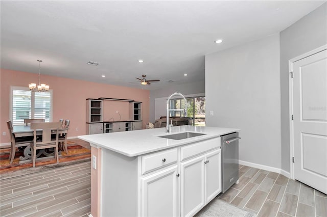 kitchen with plenty of natural light, ceiling fan with notable chandelier, a center island with sink, and a sink