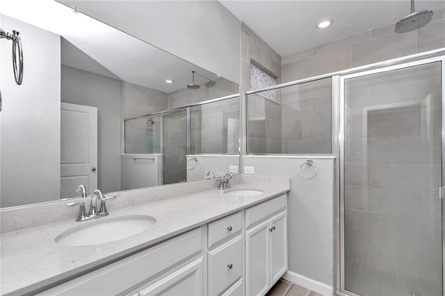 bathroom with a shower stall, double vanity, and a sink