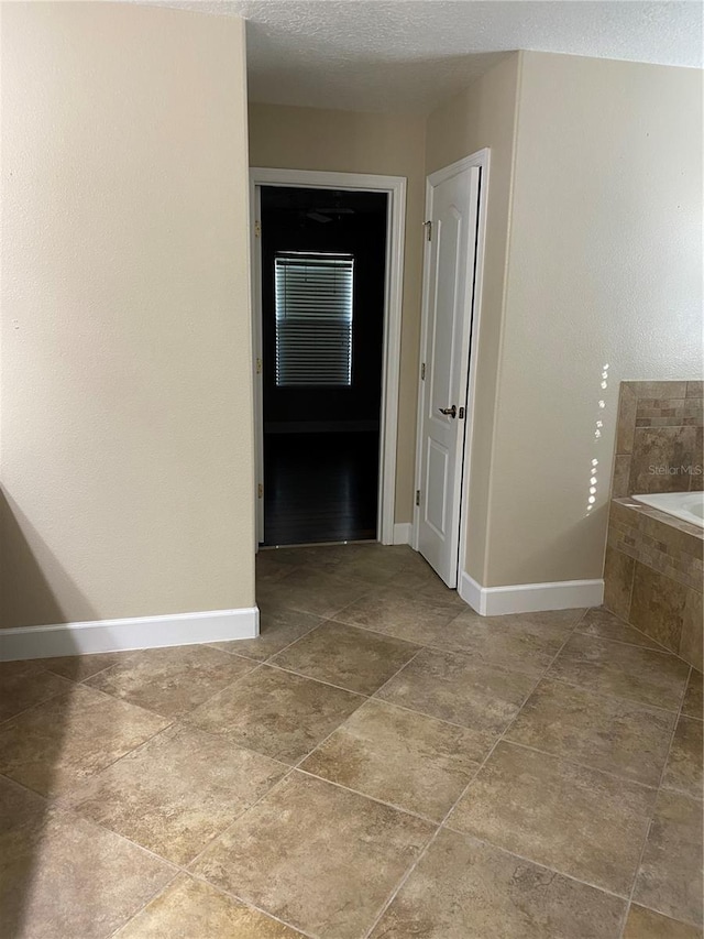 hall with a textured ceiling and baseboards