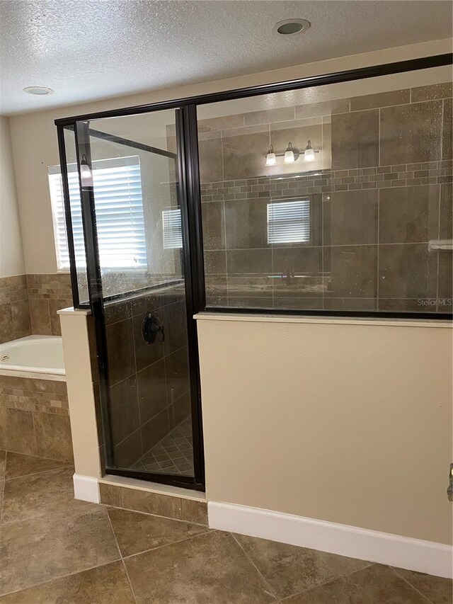 bathroom with a stall shower, a garden tub, a textured ceiling, and tile patterned floors