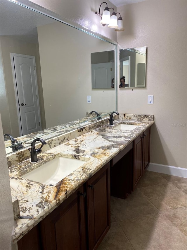 full bathroom featuring tile patterned floors, a sink, baseboards, and double vanity