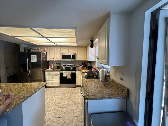 kitchen featuring white cabinetry, stone countertops, appliances with stainless steel finishes, and light tile patterned flooring