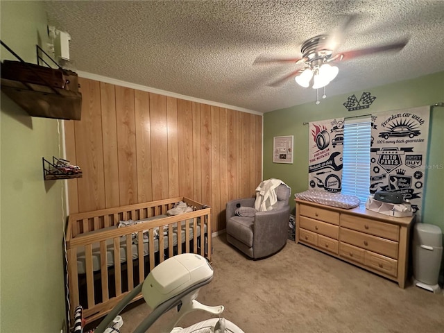 bedroom with wooden walls, a textured ceiling, a ceiling fan, and carpet flooring