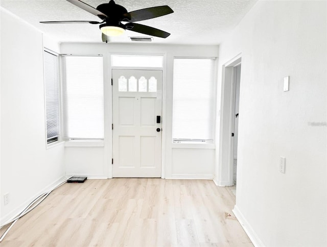 entryway featuring a wealth of natural light, a textured ceiling, visible vents, and wood finished floors