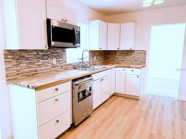 kitchen featuring white cabinets, butcher block countertops, stainless steel appliances, and a sink