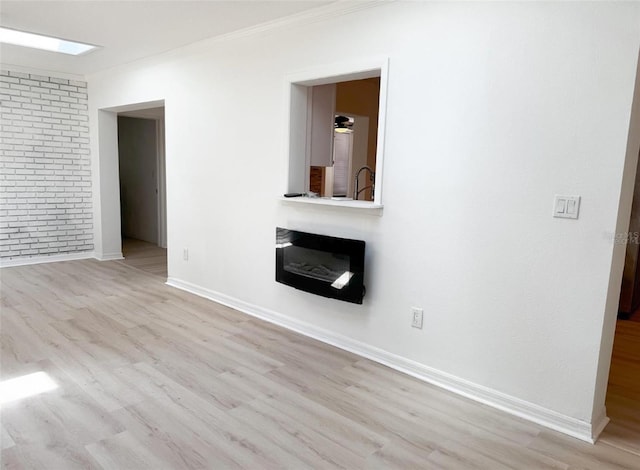 unfurnished living room with a skylight, baseboards, wood finished floors, and ornamental molding