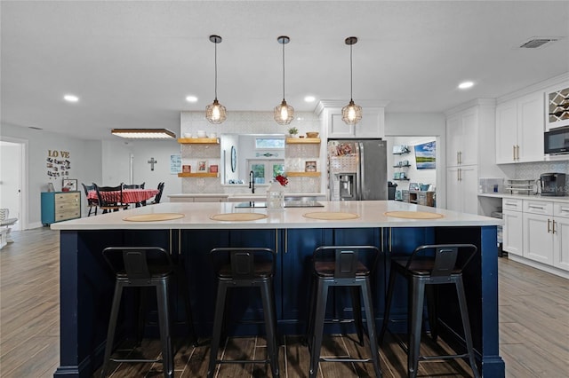 kitchen with white cabinetry, light countertops, stainless steel refrigerator with ice dispenser, backsplash, and open shelves