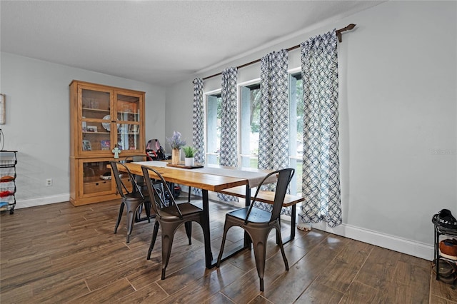 dining room with dark wood-style floors, a textured ceiling, and baseboards