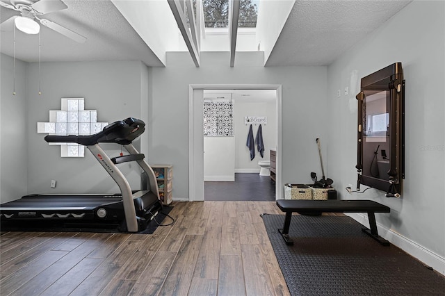 workout room featuring a ceiling fan, a textured ceiling, baseboards, and wood finished floors