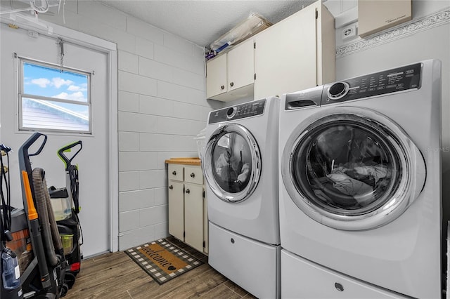 washroom with concrete block wall, cabinet space, wood finished floors, independent washer and dryer, and a textured ceiling