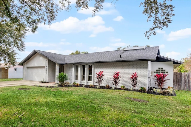 mid-century home featuring an attached garage, brick siding, fence, concrete driveway, and a front lawn