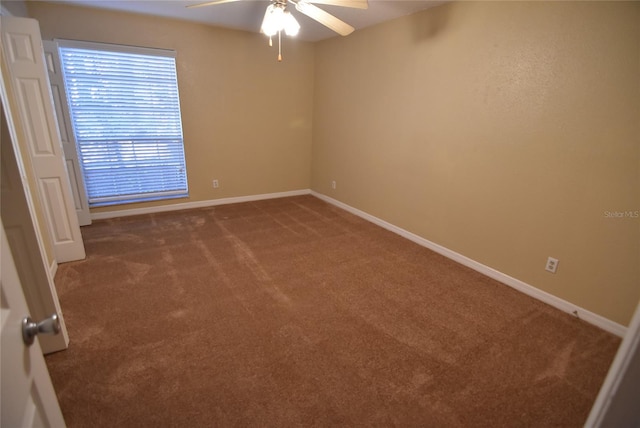 carpeted spare room with baseboards and a ceiling fan