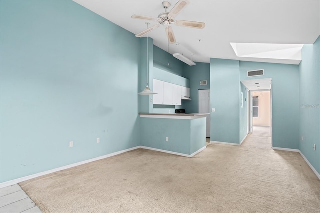 interior space with a skylight, visible vents, white cabinets, ceiling fan, and a peninsula