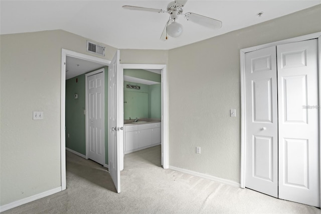 unfurnished bedroom with visible vents, light colored carpet, lofted ceiling, a sink, and a closet