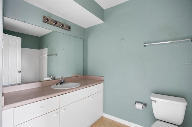 bathroom featuring baseboards, vanity, and toilet