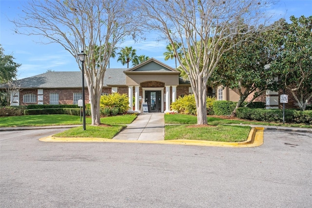 view of front of property featuring uncovered parking, a front lawn, and brick siding