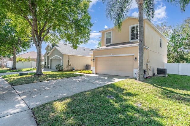 traditional home with an attached garage, central AC, fence, stucco siding, and a front lawn