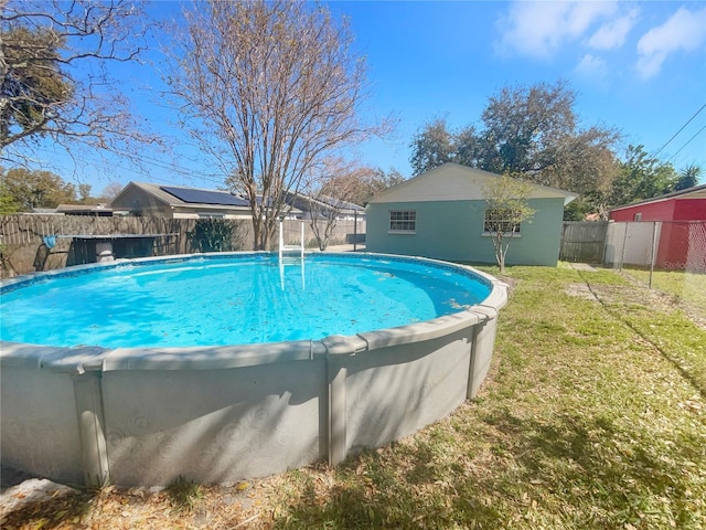 view of swimming pool with a fenced backyard, a lawn, a fenced in pool, and an outdoor structure