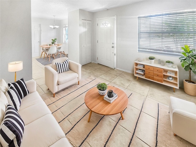 living room with a chandelier, tile patterned flooring, and baseboards