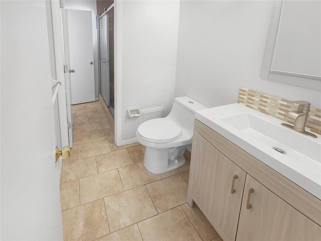 bathroom featuring toilet, vanity, backsplash, tile patterned floors, and a stall shower