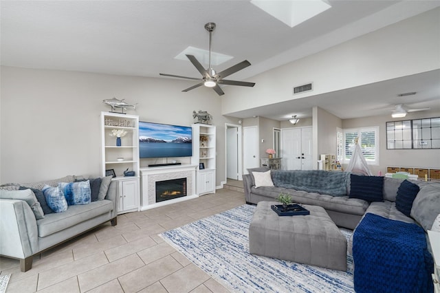 living room with a glass covered fireplace, vaulted ceiling, visible vents, and ceiling fan