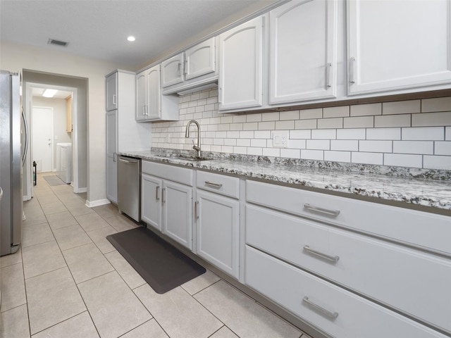 kitchen with visible vents, decorative backsplash, appliances with stainless steel finishes, light tile patterned flooring, and a sink