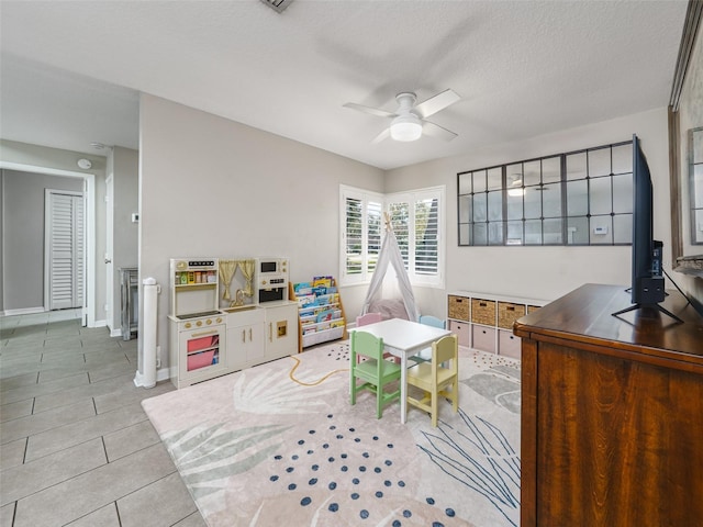 game room with tile patterned flooring, ceiling fan, baseboards, and a textured ceiling