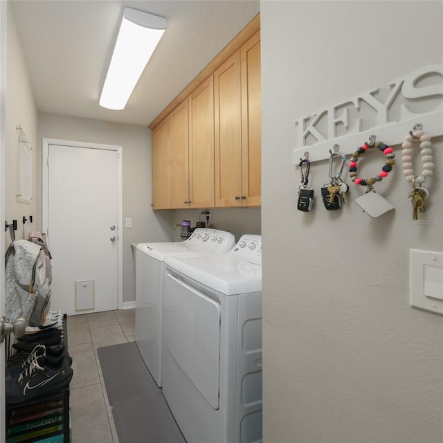 washroom with light tile patterned floors, washing machine and dryer, and cabinet space