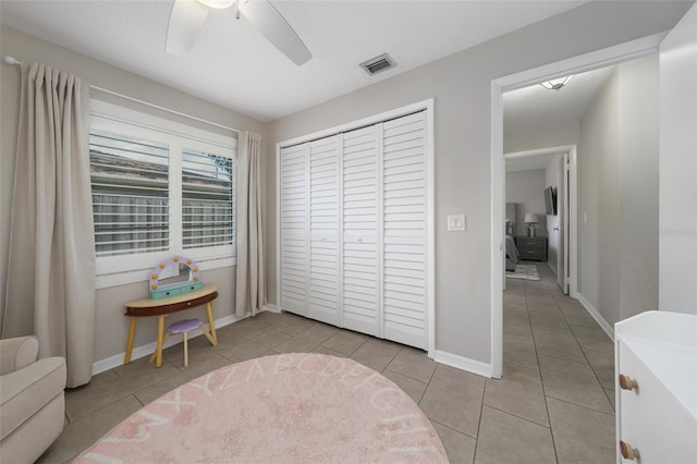 bedroom with visible vents, baseboards, ceiling fan, a closet, and light tile patterned flooring