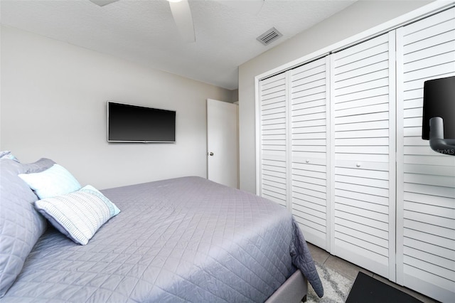 bedroom featuring a textured ceiling, a closet, visible vents, and a ceiling fan