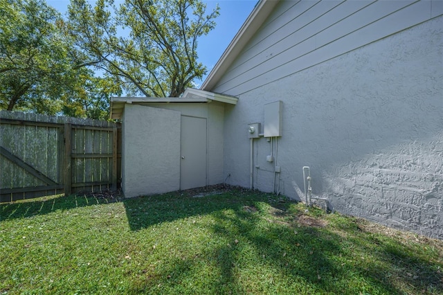 view of property exterior featuring stucco siding, fence, and a yard