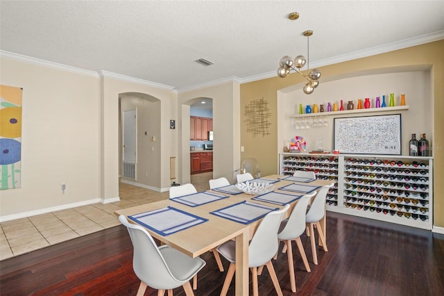 12824 Penshurst Ln, Windermere, FL 34786 - dining area featuring arched walkways, crown molding, a textured ceiling, and wood finished floors