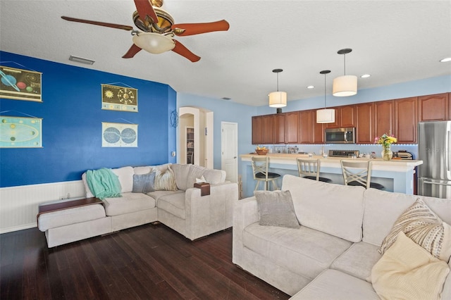 12824 Penshurst Ln, Windermere, FL 34786 - living room with visible vents, arched walkways, a wainscoted wall, dark wood-style flooring, and a textured ceiling