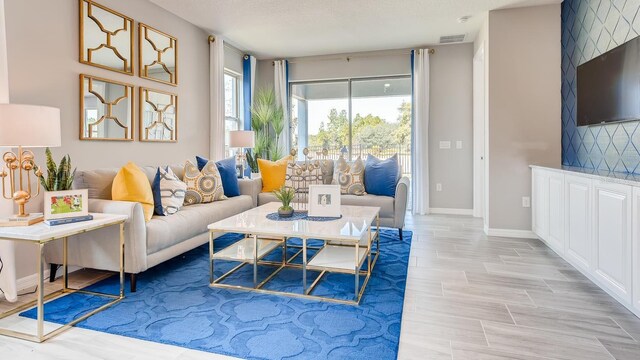 living area featuring wood finish floors, visible vents, a textured ceiling, and baseboards