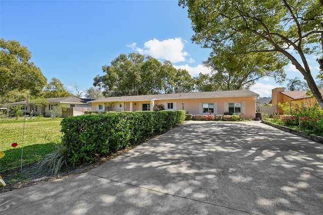 ranch-style home with fence, a front lawn, and stucco siding