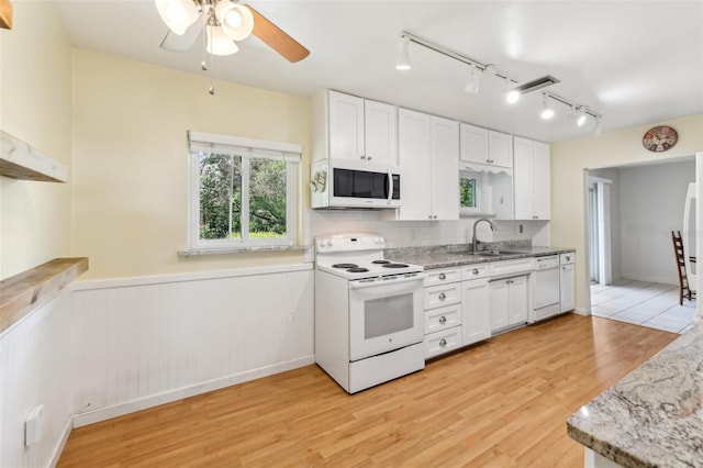 kitchen with white appliances, a sink, white cabinets, light wood-type flooring, and light stone countertops