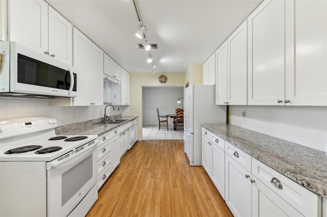 kitchen featuring white appliances, tasteful backsplash, white cabinets, and a sink