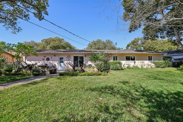 back of property featuring a lawn and stucco siding