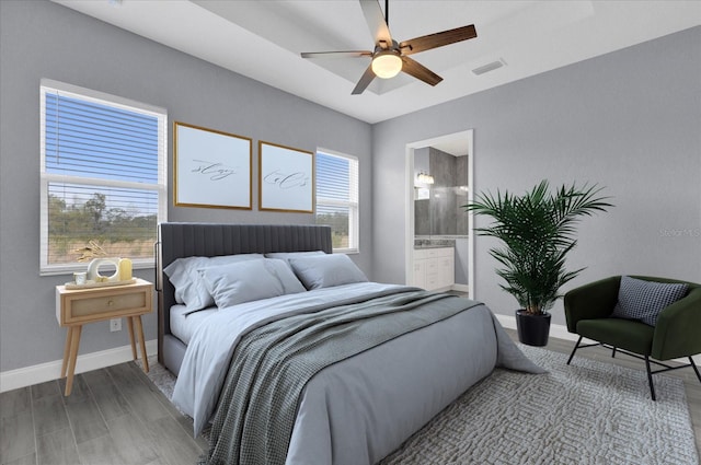 bedroom featuring visible vents, baseboards, ceiling fan, light wood-type flooring, and connected bathroom