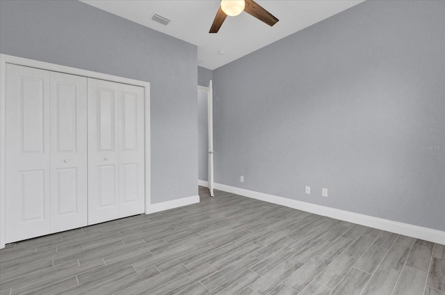 unfurnished bedroom with baseboards, visible vents, a closet, and wood tiled floor